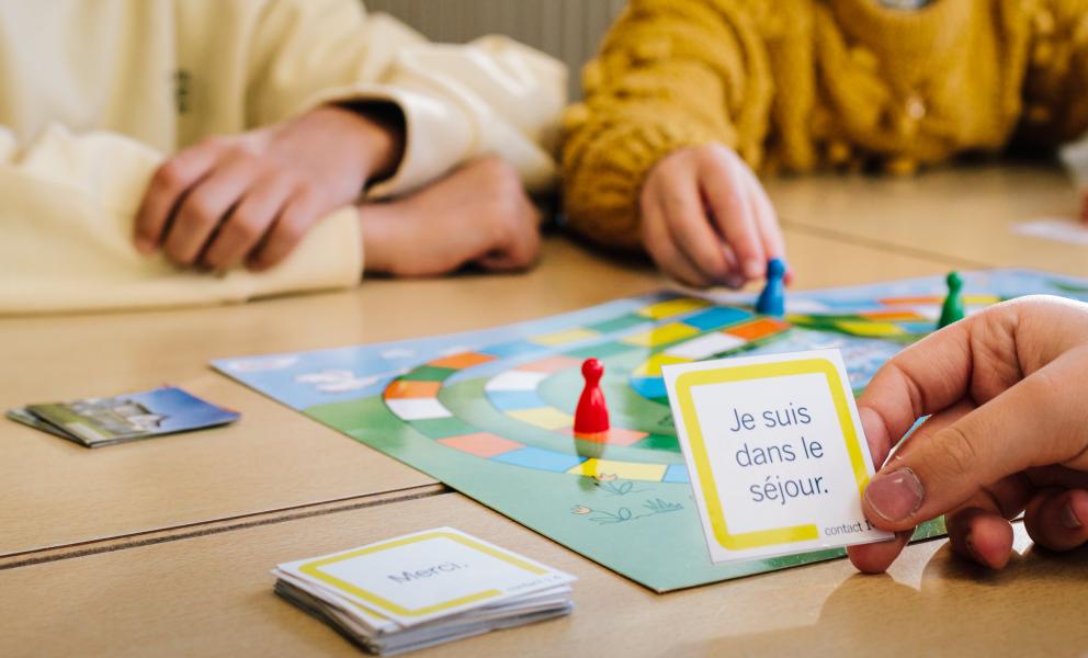 Handen van kinderen die samen een spel spelen om Frans te leren