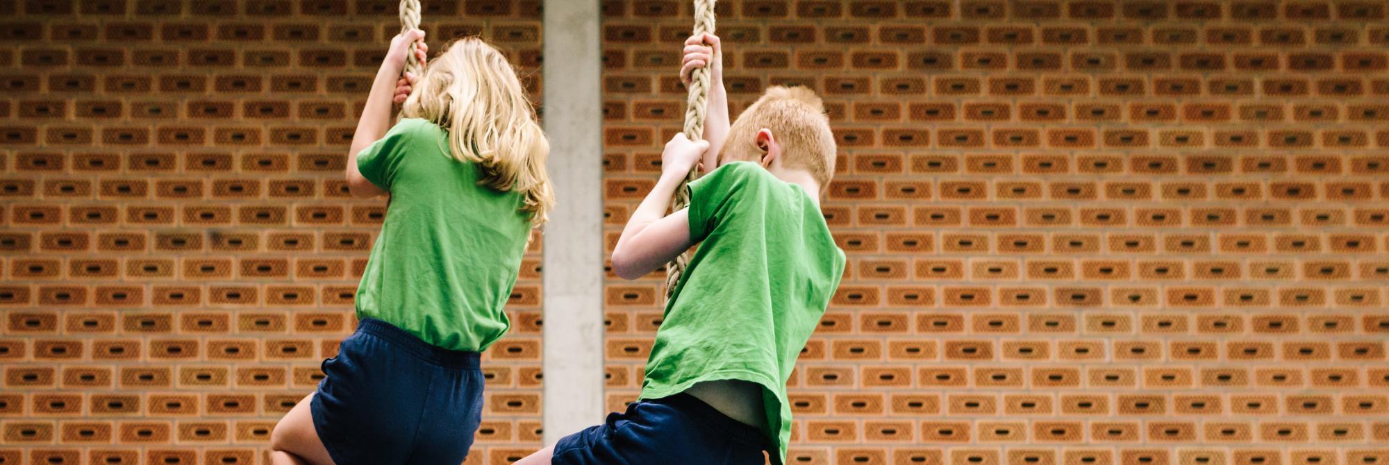 Twee kinderen slingeren naast elkaar aan een touw